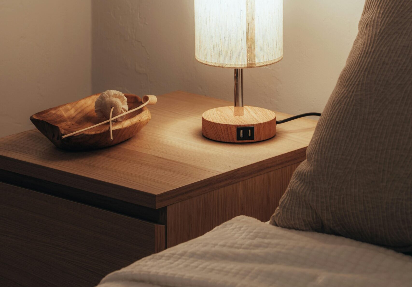 Nightstand bedroom size and style example with a mid height wooden nightstand beside a modern bed in a minimal Canadian bedroom