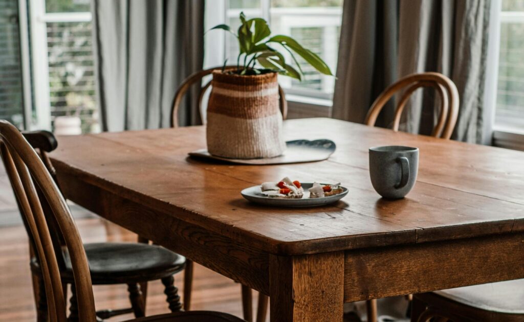 How to choose a dining table for an open concept home in Canada with a round oak table and woven chairs in a bright modern kitchen dining space